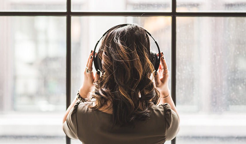 back of woman listening to music in front of window